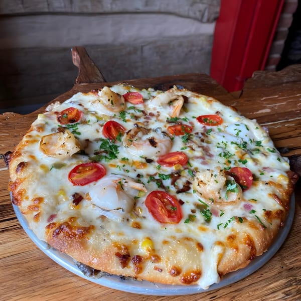 The Humble Tomato's shrimp pizza, topped with melted cheese, cherry tomatoes, and fresh herbs.