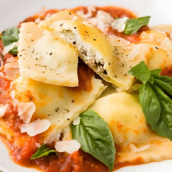 Close-up of ravioli with tomato sauce, parmesan, and basil, one ravioli cut open.