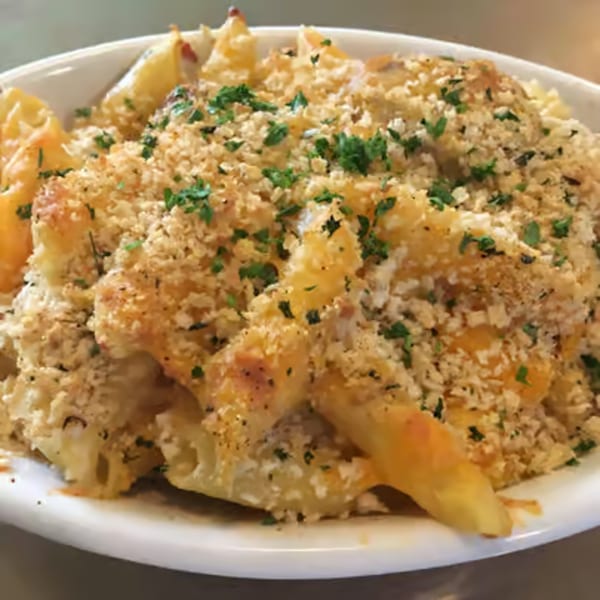 Baked pasta dish with a golden-brown breadcrumb topping and fresh parsley in a white bowl.